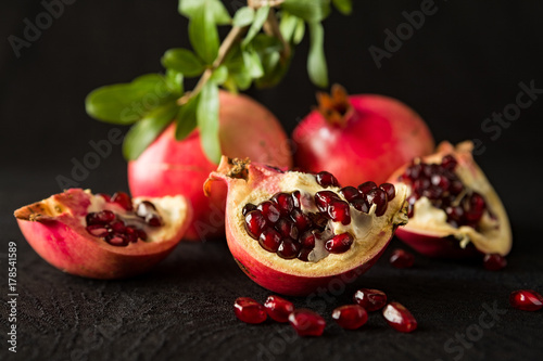 closeup-of-ripe-pomegranate-fruits-and-seeds-over-a-textured-black-background
