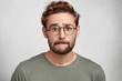 © wayhome.studio - Worried bearded guy in eyewear, bites lower lip, anticipate important decision or feels nervous before doctor`s visit, being afraid of it. Uncertain attractive male nerd worries before final exam