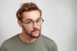© wayhome.studio  - Portrait of young man with specific appearance looks through round glasses, listens attentively to interlocutor, going to speak his mind or prove rightness. People and body language concept.