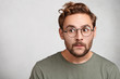 © wayhome.studio  - Headshot of attractive stylish youngster or male wonk wears round spectacles, looks curious aside, tries to overhear somethinng important. Caucasian bearded young man with guarded look, worries