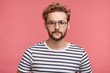 © wayhome.studio - Portrait of hipster male in striped t shirt, wears round spectacles, has trendy hairstyle, looks confidently into camera, going to present lecture or conduct seminar for people, isolated on pink wall
