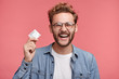 © WHstudio Leushin N - Cheerful bearded man holds condom, being glad to have unforgettable night with woman, wants to repeat once again. Positive stylish man promotes healthy lifestyle and relationship, shows how protect