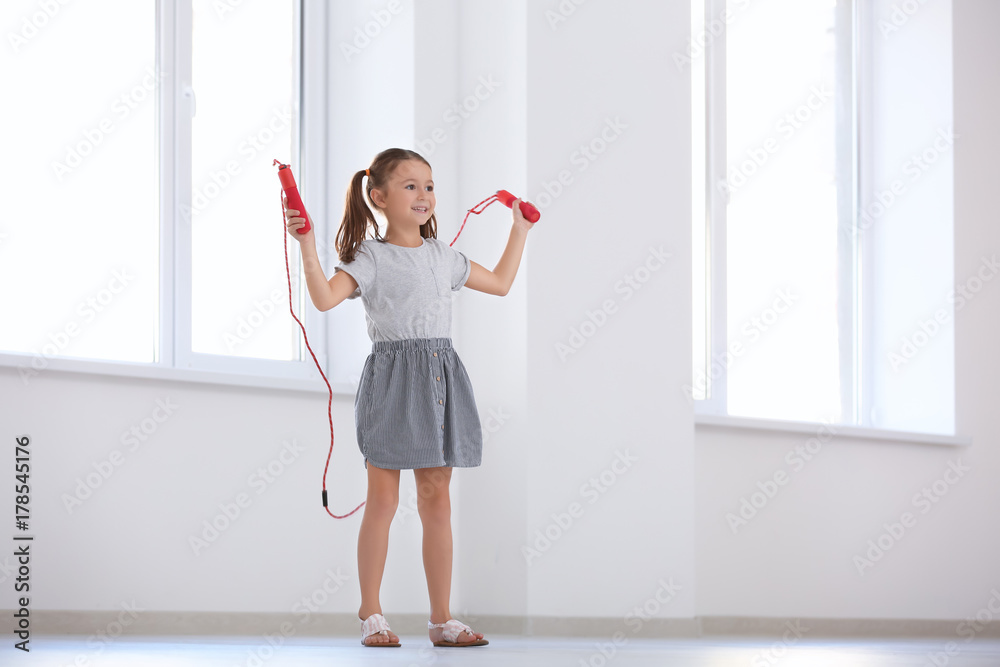 Adorable girl skipping rope indoors