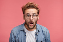 Stupefied Attractive Young Bearded Man Looks With Astonishment Into Camera, Being Amazed With Negative News. Emotional Hipster Guy Expresses Surprisment, Doesn`t Believe His Eyes. Facial Expression