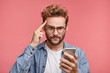 © WHstudio Leushin N - Portrait of serious male keeps finger on temples reads information on mobile phone, upset to find out about raising sales. Stressful puzzled male model uses smart phone to find out news from internet