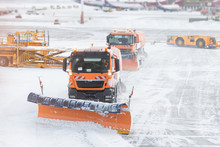 Snowplow Removing Snow From Runways And Roads In Airport During Snow Storm, View Through Window
