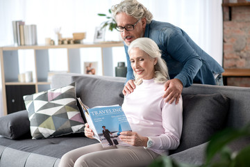 Wall Mural - Happy senior man and woman entertaining with journal at home