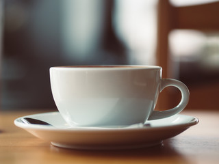 Cup of hot coffee served on wooden table in the cafe.