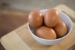 Brown eggs in bowl on cutting board