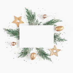 christmas composition. paper blank, christmas tree branches, golden decorations on white background.