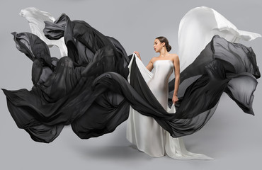 fashion portrait of a beautiful woman in a white and black dress. The fabric flies in the wind.