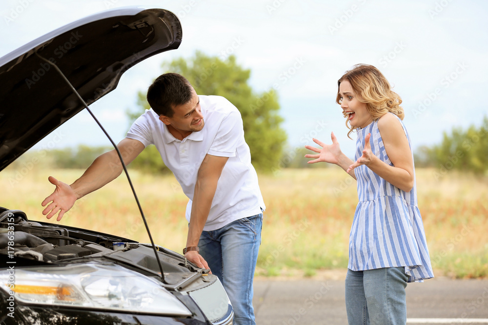 Young couple standing near broken car