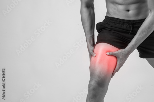 Fotografía Young sport man with strong athletic legs holding knee with his hands in pain after suffering ligament injury isolated on white