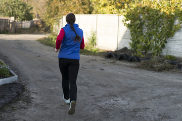 A sports girl is running on a dirt road