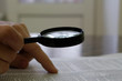 © Irina - the person reads the document through a magnifying glass