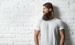© nyul - Trendy young bearded man against white brick wall
