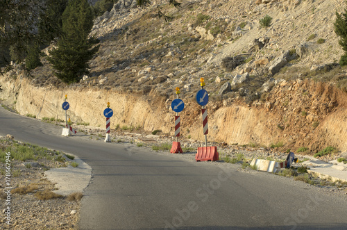 Fotografie, Obraz Road signs direction of movement at the foot of the mountain, with rockfalls on