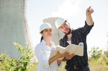 two engineers standing at electricity station, discussing plan