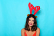Beautiful woman with reindeer horns. Studio shot on blue background