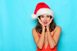 Excited beautiful woman with santa hat. Studio shot on blue background.