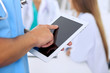 © rogerphoto - Surgeon doctor using tablet computer, close-up of hands at touch pad screen