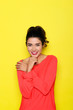 Beautiful positive woman covering chest with hands on yellow background.
