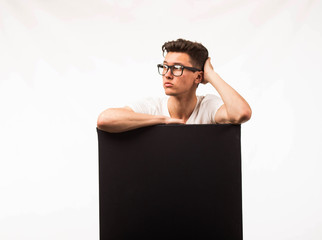 Young pensive man portrait of a confident businessman showing presentation, pointing paper placard gray background. Ideal for banners, registration forms, presentation, landings, presenting concept.