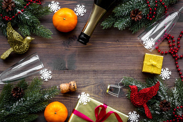 New year eve background. Spruce branch, gift, glasses, tangerines on wooden background top view copyspace