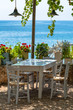 Table and chairs next to the sea in a Greek taverna.