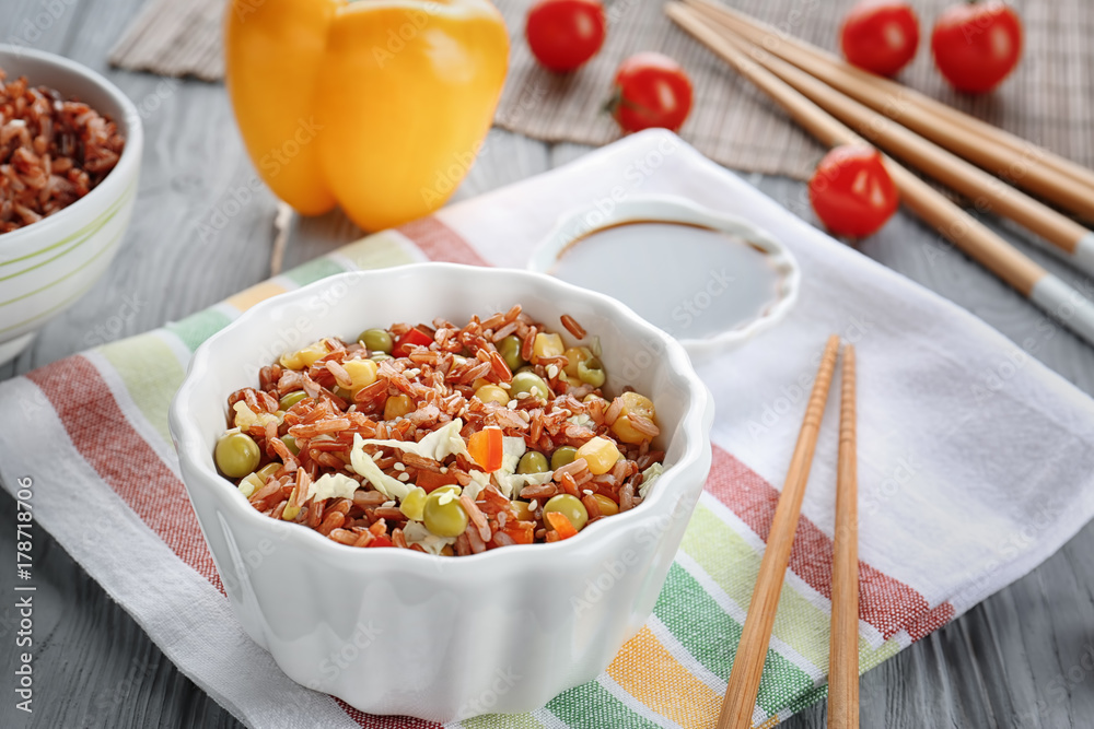Bowl with brown rice and vegetables on table