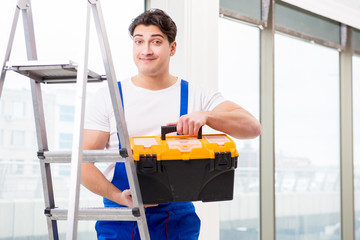 Young repairman climbing ladder at construction  site