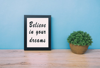Wall Mural - Motivational and inspirational life quotes - Believe in your dreams. Frame and plant with teal blue background, retro style.
