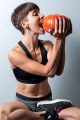 sports girl doing yoga with a pumpkin on a holiday of halloween