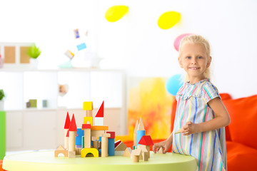 Canvas Print - Cute girl playing with blocks on table indoor