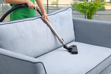 Wall Mural - Woman cleaning couch with vacuum cleaner at home