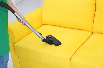 Wall Mural - Woman cleaning couch with vacuum cleaner at home