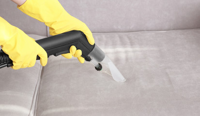 Wall Mural - Woman cleaning couch with vacuum cleaner at home