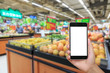 © ABCDstock - Hand holding smartphone with white blank screen and blurred supermarket fruit background