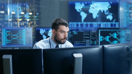 Fototapete - In the Monitoring Room Technical Operator Attentively Monitors Stability of the System. He's Surrounded By Screens Showing Technical Data. Shot on RED EPIC-W 8K Helium Cinema Camera.
