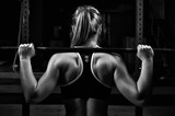 Fototapeta Tulipany - Back view young female doing barbell squats in gym
