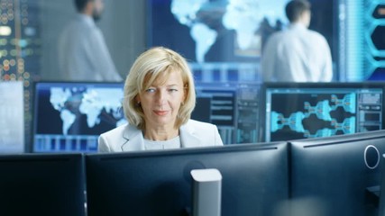 Fototapete - System Monitoring Room Professional Female Operator Observes Correct Functioning of the Facility. In the Background People Working with Interactive Map. Shot on RED EPIC-W 8K Helium Cinema Camera.