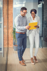 Business people walking through office lobby and discussing document.