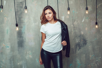 Sexy woman in white t-shirt and jacket on the gray background with lamps. Mock-up.