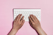 © dohee - man hand type a text wireless keyboard on the pink background.