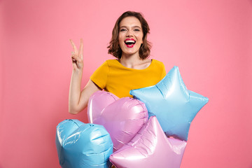 Poster - Close-up photo of happy birthday girl with red lips holding balloons, showing peace gesture, looking at camera