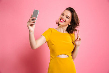 Poster - Cute pretty girl with bright makeup showing peace gesture while taking selfie on mobile phone