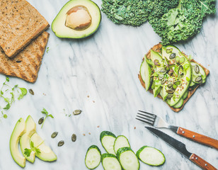 Wall Mural - Healthy green veggie breakfast. Sandwich with avocado, cucumber, kale, kress sprouts, pumpkin seeds over marble background, top view, copy space. Vegan, weight loss, clean eating, detox food concept