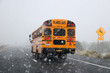 School bus in snow storm. Yellow classic school bus rides on the road during a sudden snowfall. Bad weather background. Danger concept.