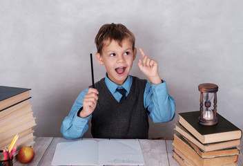 Wall Mural - The European school student behind a desk with gesture of an ekrik.