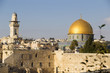 Old city quarter of ancient Jerusalem with light brown stone walls of houses, high tower and dome of the mosque